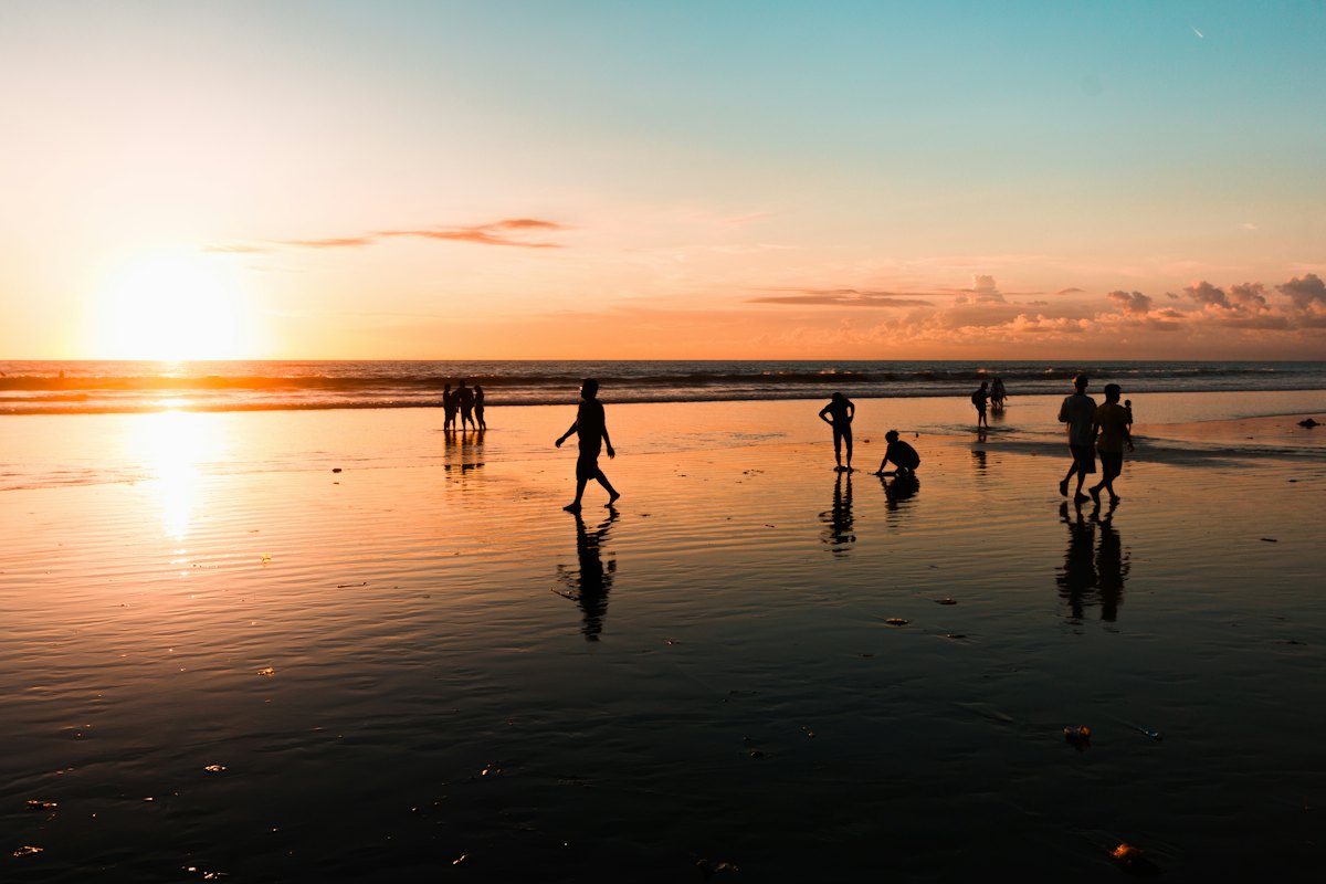 A group of people on the sand at sunset
